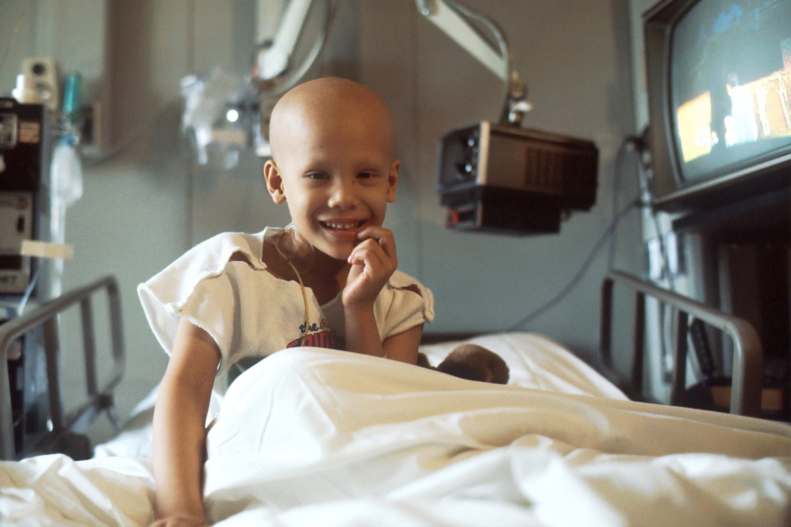 child with cancer sitting on bed