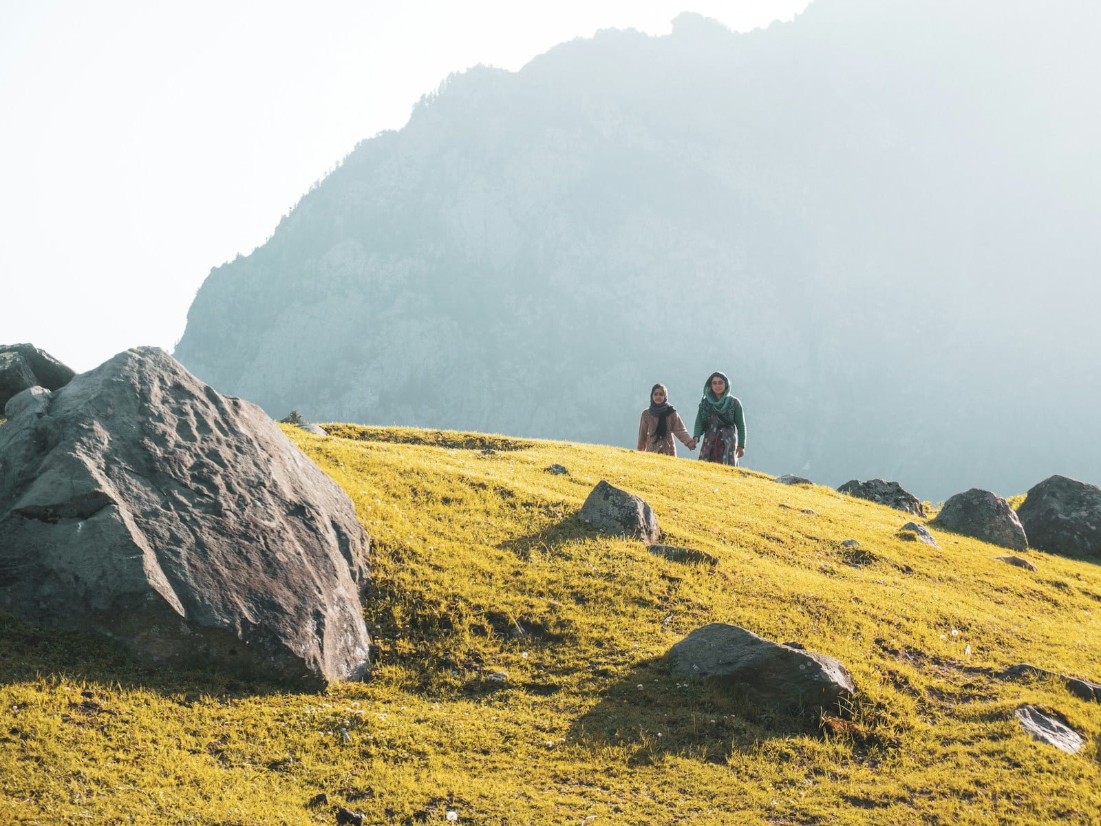 two person walking on mountain during daytime
